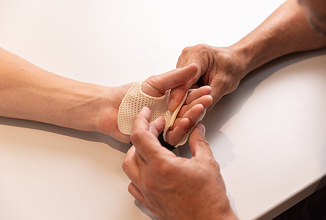 Patient trainiert Handbeweglichkeit mit Rehabilitationsgerät