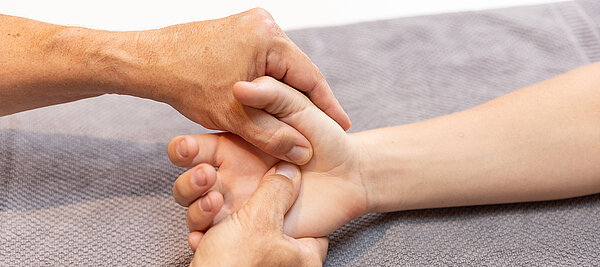 Therapeut führt Handrehabilitation mit Patient durch