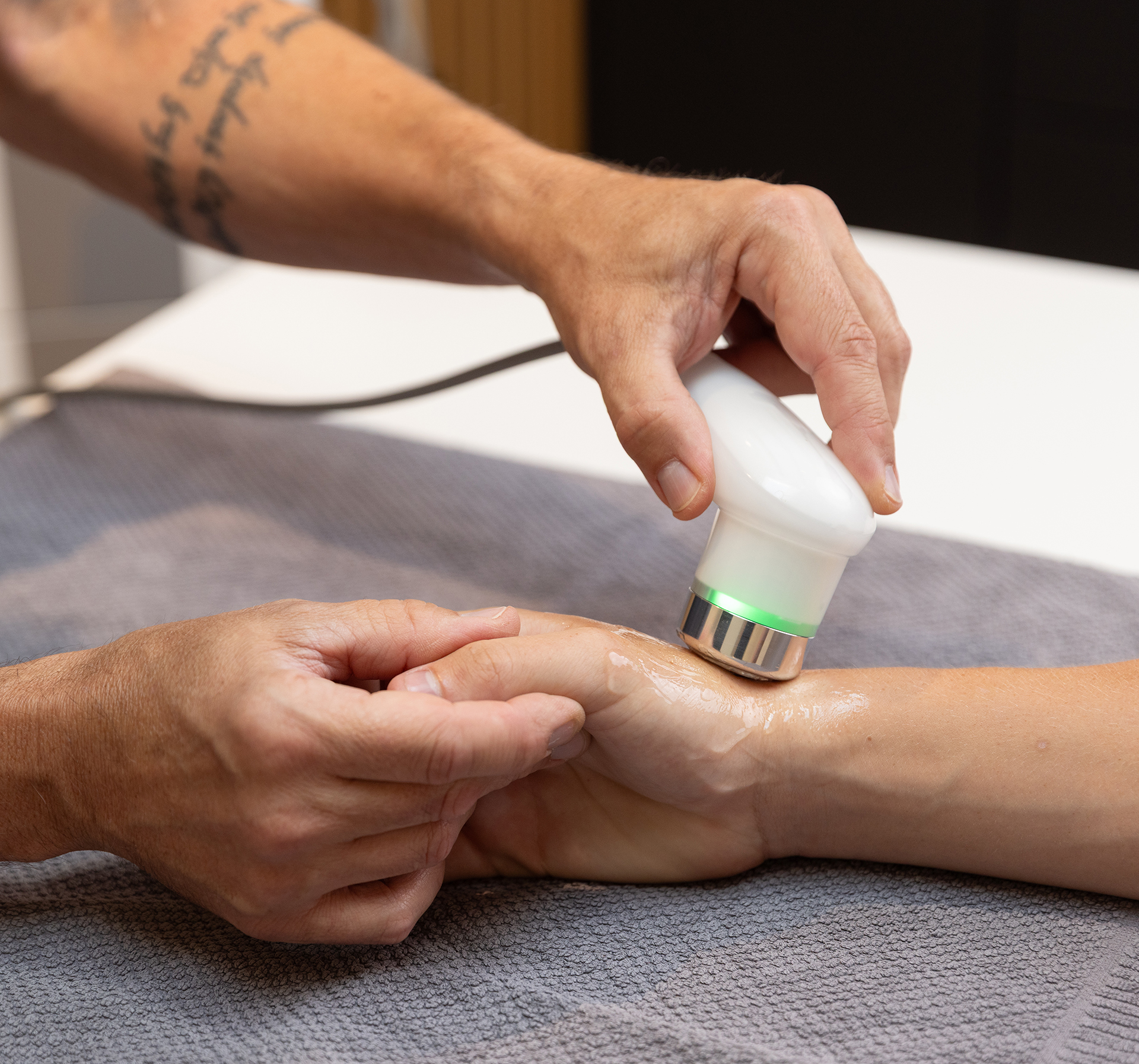 Therapeut behandelt Patientin an der Hand mit Lasergerät